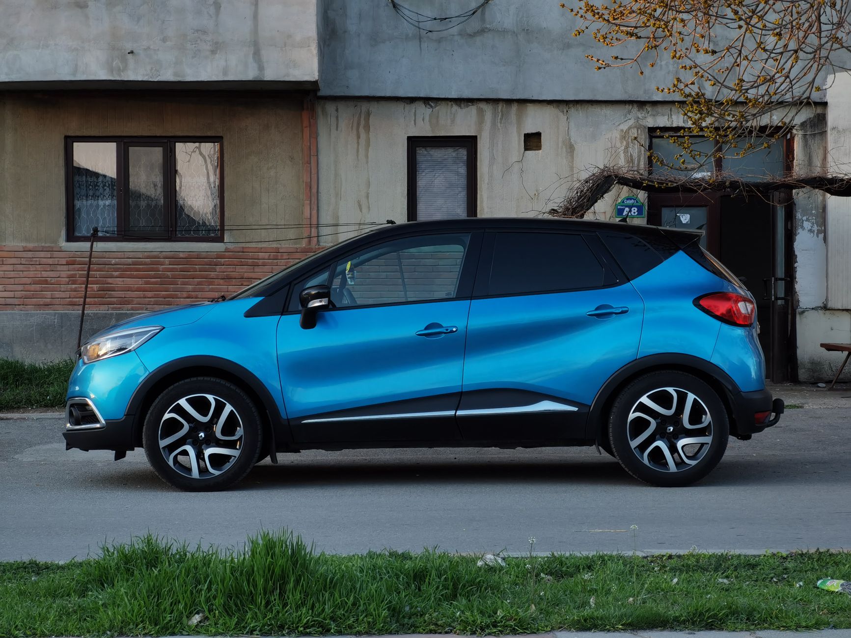 Niebieski miejski crossover Mitsubishi zaparkowany przy starej kamienicy