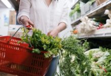Jak wybierać ekologiczną żywność w sklepie: praktyczny przewodnik dla początkujących Osoba trzyma koszyk z ekologicznymi zielonymi warzywami w sklepie