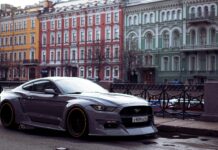 Szary Ford Mustang zaparkowany przy kolorowych kamienicach w mieście