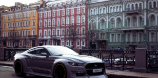 Ford Mustang jako auto na co dzień – czy muscle car nadaje się do miasta Szary Ford Mustang zaparkowany przy kolorowych kamienicach w mieście
