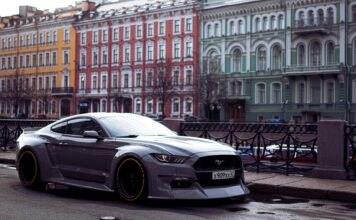 Szary Ford Mustang zaparkowany przy kolorowych kamienicach w mieście