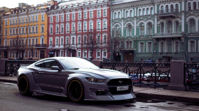 Szary Ford Mustang zaparkowany przy kolorowych kamienicach w mieście