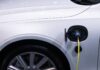 Jak dbać o hybrydę Toyoty, by bateria wytrzymała jak najdłużej i nie zrujnowała budżetu Białe auto elektryczne Toyota podłączone do ładowania, zbliżenie gniazda