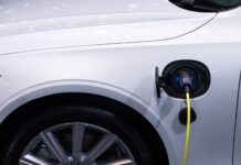 Jak dbać o hybrydę Toyoty, by bateria wytrzymała jak najdłużej i nie zrujnowała budżetu Białe auto elektryczne Toyota podłączone do ładowania, zbliżenie gniazda
