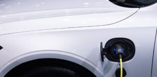 Białe auto elektryczne Toyota podłączone do ładowania, zbliżenie gniazda