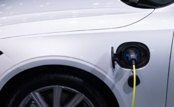 Jak dbać o hybrydę Toyoty, by bateria wytrzymała jak najdłużej i nie zrujnowała budżetu Białe auto elektryczne Toyota podłączone do ładowania, zbliżenie gniazda