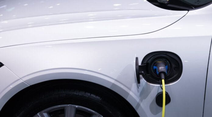 Jak dbać o hybrydę Toyoty, by bateria wytrzymała jak najdłużej i nie zrujnowała budżetu Białe auto elektryczne Toyota podłączone do ładowania, zbliżenie gniazda