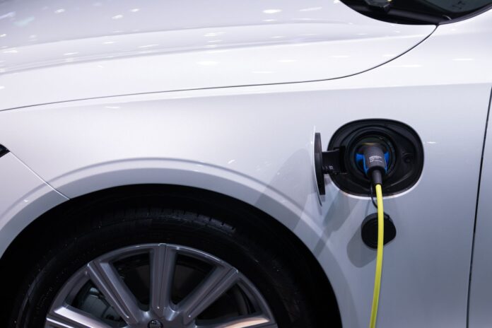 Białe auto elektryczne Toyota podłączone do ładowania, zbliżenie gniazda Białe auto elektryczne Toyota podłączone do ładowania, zbliżenie gniazda