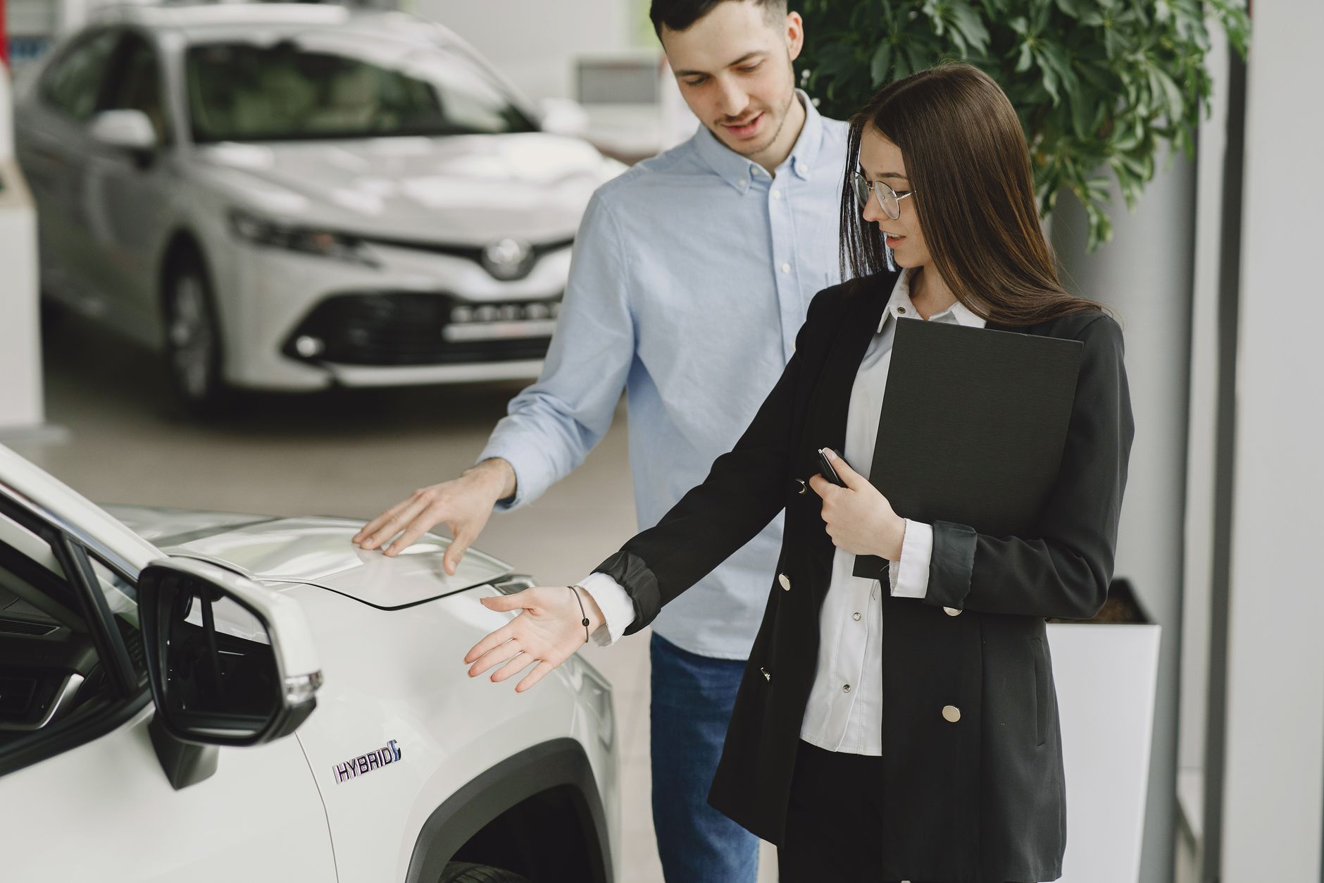 Klient z doradcą oglądają hybrydową Toyotę w salonie samochodowym