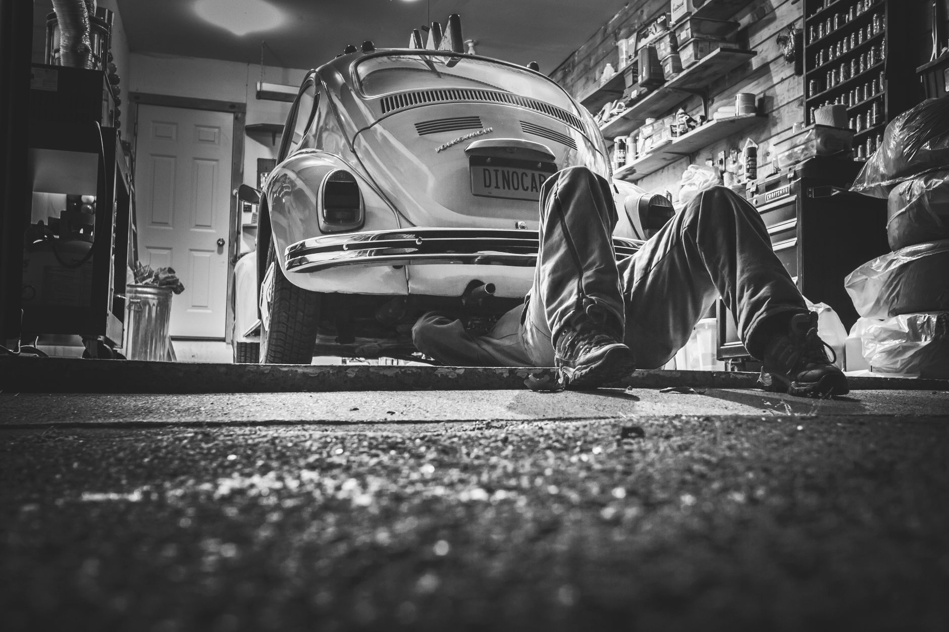 Mechanik pracujący pod klasycznym Volkswagenem Beetle w garażu