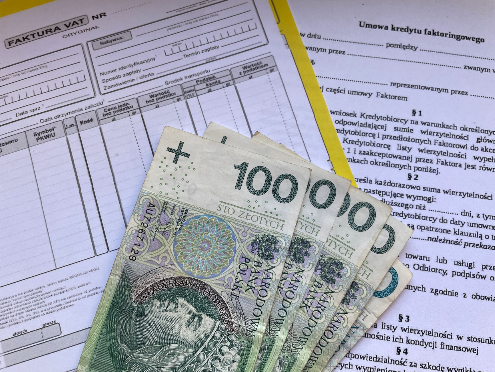 Banknoty 100 zł na fakturze VAT i umowie factoringu