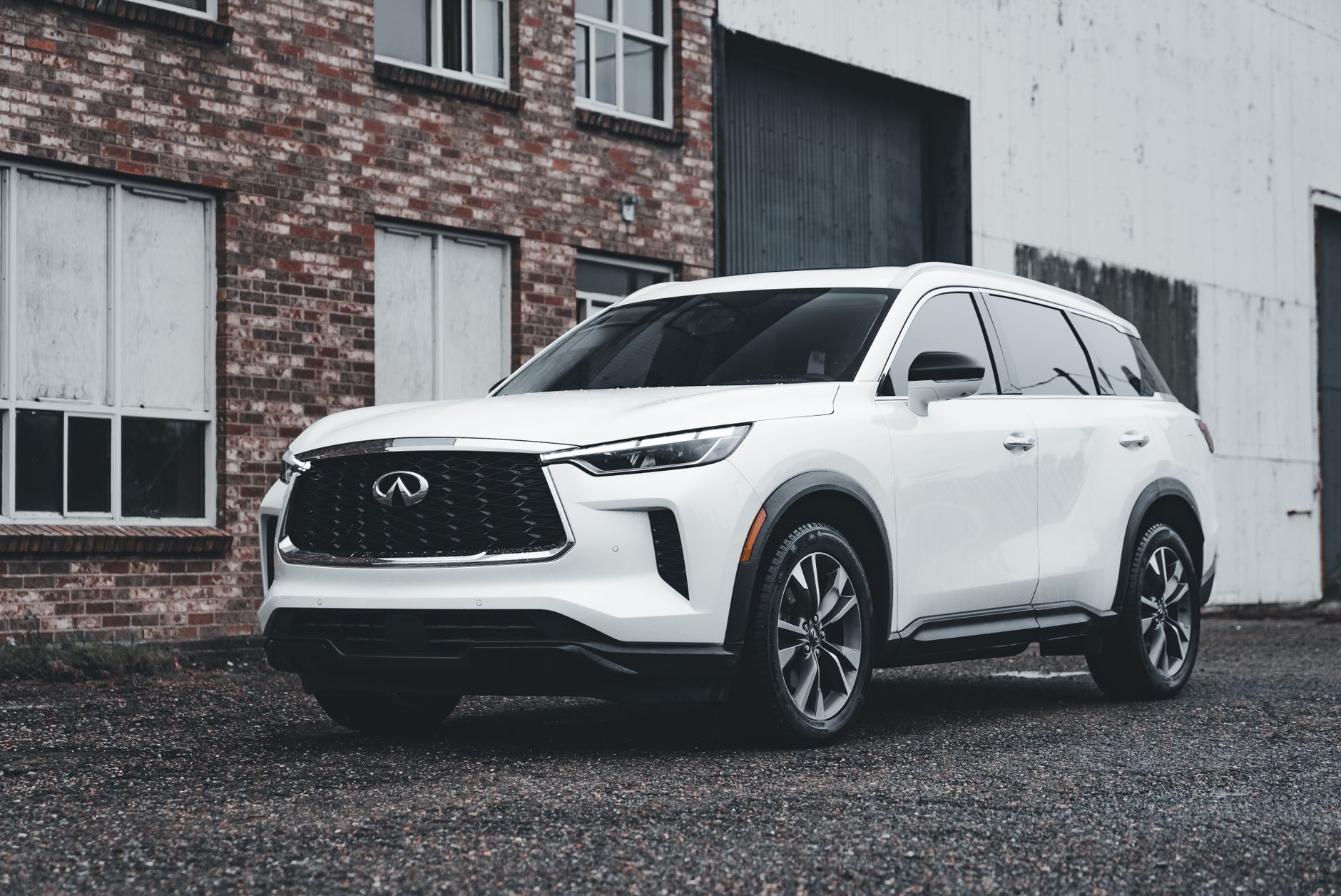Biały luksusowy SUV zaparkowany przed ceglanym budynkiem