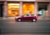 Czerwony kompaktowy samochód Skoda pędzący ulicą w mieście